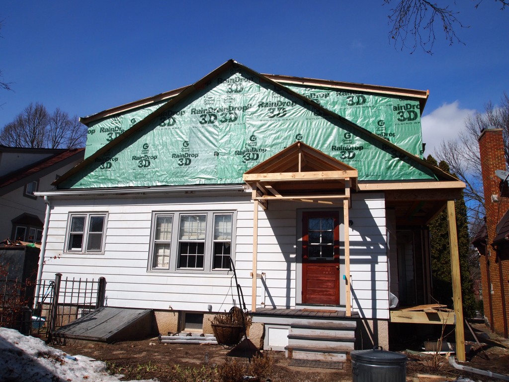 Friday afternoon, the house is wrapped. Note the new porch roof.