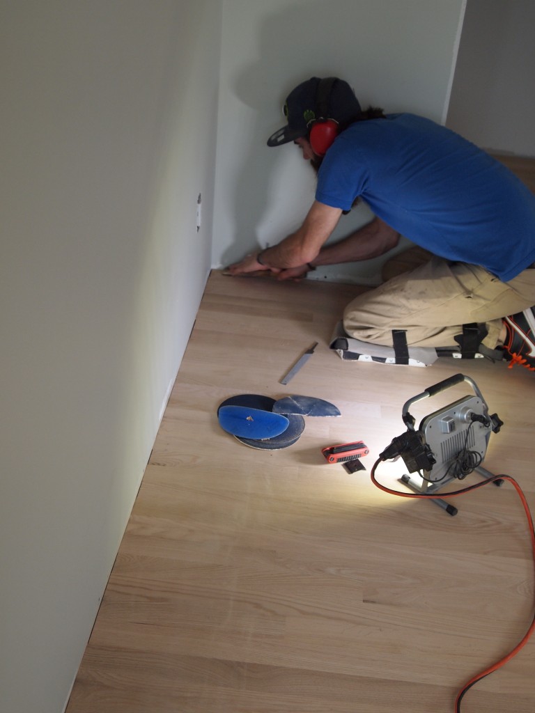 After the floor is sanded, Jason carefully scrapes the corners smooth.