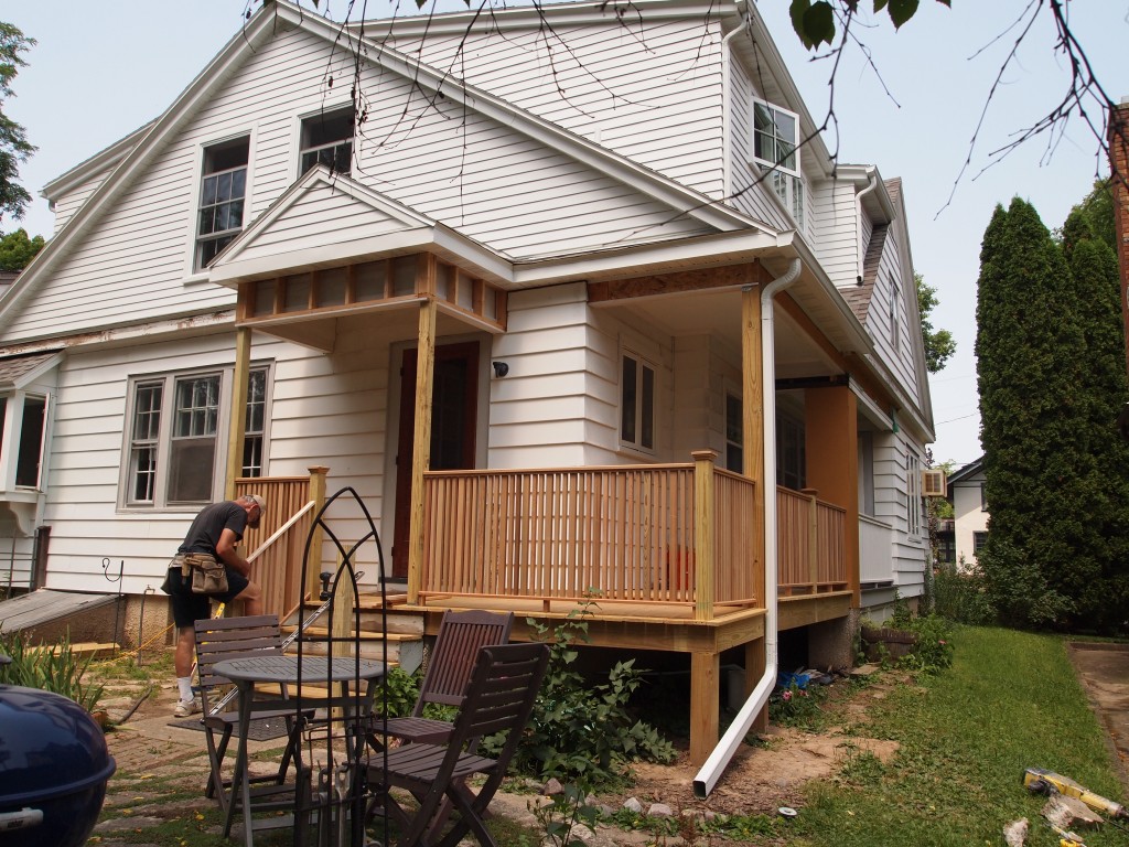 Deck and railing installed outside. Notice the new gutters and downspout.